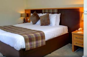 德里门Buchanan Arms Hotel & Leisure Club的酒店客房设有一张大床和一个床头柜。