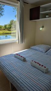 圣让德洛讷Cottage flottant jacuzzi privé en option gamme supérieure的一张带两个枕头的床和窗户