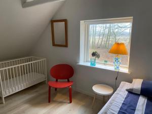 吉弗Skønt hus på landet tæt på Billund的一间卧室配有一张床、一张红色椅子和一个窗户