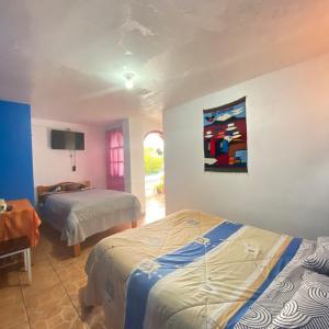 奥塔瓦洛Hostal Chasqui的一间卧室设有两张床,墙上配有电视。