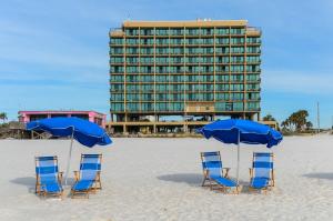 格尔夫海岸Phoenix All Suites by Brett Robinson的海滩上的四把椅子和遮阳伞