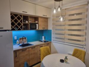 亚霍里纳Vila Jahor Apartman Miro的厨房配有白色的桌子和黄色的椅子