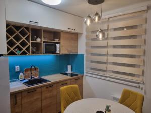 亚霍里纳Vila Jahor Apartman Miro的厨房配有木制橱柜和一张带黄色椅子的桌子。