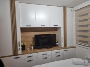 亚霍里纳Vila Jahor Apartman Miro的一间带电视和白色橱柜的卧室