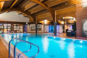 雷迪奇经典英国修道院高尔夫酒店&SPA的一座大型游泳池,位于一栋带木制天花板的建筑内