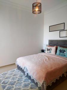 艾西拉Rosewood, un appartement de rêve à Asilah Marina Golf的一间卧室配有一张大床和一个吊灯。