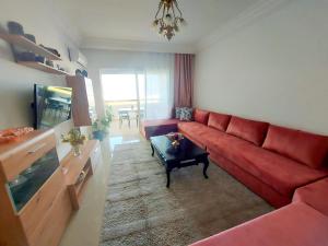 艾西拉Rosewood, un appartement de rêve à Asilah Marina Golf的客厅配有红色沙发和电视