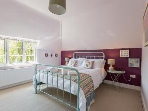 伯利Mast Cottage的一间卧室配有一张紫色墙床