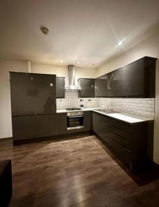 伦敦Alarabi Apartments-Peckham的一间铺有木地板的大型厨房,配有黑色橱柜