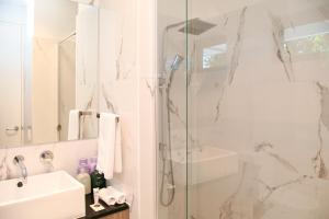 KeswickHilton Executive Apartments的带淋浴和盥洗盆的白色浴室