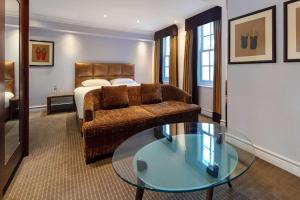 伦敦Radisson Blu Edwardian Bond Street Hotel, London的酒店客房设有床、沙发和玻璃桌。