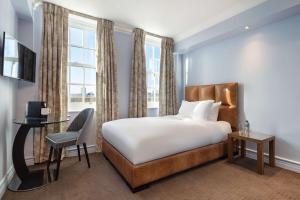 伦敦Radisson Blu Edwardian Bond Street Hotel, London的一间卧室配有一张床、一张书桌和一个窗户。