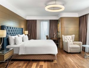伊斯坦布尔伊斯坦布尔西西里丽笙布鲁酒店的卧室配有一张白色大床和一把椅子