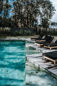 Shoalhaven HeadsBangalay Luxury Villas的一个带躺椅的游泳池和一个泳池景泳池