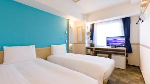 松户市Toyoko Inn Matsudo eki Higashi guchi的酒店客房设有两张床和电视。