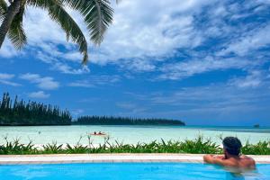 Oro Bay松林岛子午线度假酒店的坐在游泳池里看海洋的人