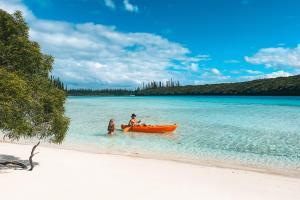 Oro Bay松林岛子午线度假酒店的海滩上划独木舟的男人和女人