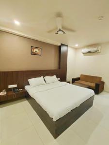 艾哈迈达巴德Hotel Palav Palace的卧室配有一张白色的大床和一张沙发。