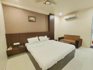 艾哈迈达巴德Hotel Palav Palace的卧室配有一张白色大床和一把椅子