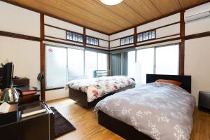 东京Kitazawa Cozy House的一间卧室设有两张床、一台电视和窗户。