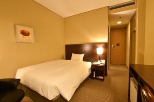 筑波Hotel Nikko Tsukuba的酒店客房设有一张大床和一张书桌。