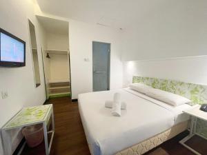 瓜埠康帕斯酒店集团兰卡威思庭酒店的卧室配有一张白色大床和一台平面电视。