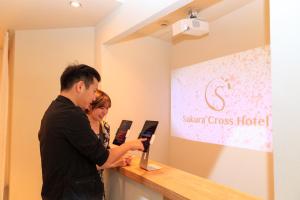 东京Sakura Cross Hotel Ueno Iriya Annex的站在柜台上的男女