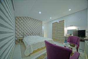 乌奇希萨尔Cappadocia Symbol Hotel的一间卧室配有一张床和两张紫色椅子