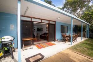 波因特卢考特Allamanda Cottage - close to beach - pet friendly的蓝色和白色的房子,设有带桌子的庭院