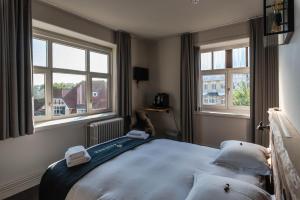 德哈恩Hotel Bonne Auberge (Adults Only)的一间卧室配有带2个枕头的床和2个窗户。