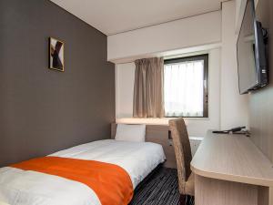 新泻新泻第一酒店的一间卧室配有一张床、一张书桌和一个窗户。
