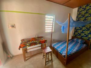 OuidahCDAC Elijah - Espace Culturel的一间卧室配有一张床、一张桌子和一张书桌