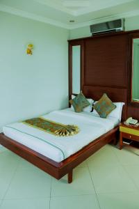 达累斯萨拉姆绿光酒店的一间卧室配有一张大床和木制床头板