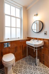 伦敦帕丁顿荣耀酒店的一间带卫生间、水槽和镜子的浴室