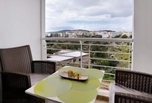 莫斯塔Valley of Honey Apartment的阳台配有绿色桌椅,设有窗户