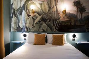 戛纳戛纳中心普鲁伊别墅酒店的卧室配有一张大床,墙上挂有绘画作品