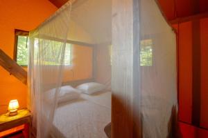 苏亚克Parc de vacances La Draille的卧室配有白色天蓬床和窗户