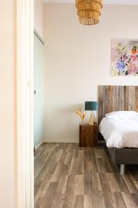 SchimmertHoeve de Binnenplaets Schimmert的卧室设有白色墙壁和一张铺有木地板的床。
