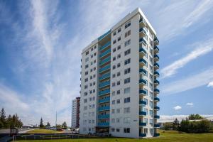 雷克雅未克Panoramic Studio Apartment with stunning view - Free Parking的一座高大的白色建筑,设有蓝色的窗户