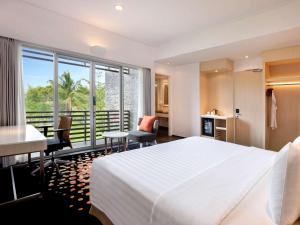 巨港巨港诺富特酒店的酒店客房,配有一张床、一张桌子和椅子
