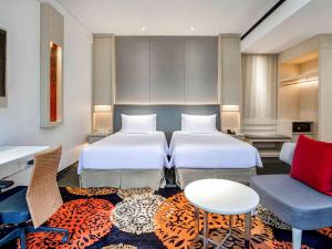 巨港巨港诺富特酒店的酒店客房设有两张床和一张桌子。