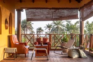 SanyangMansa Musso Treehouse Resort的一个带椅子和桌子的门廊和棕榈树