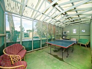 埃斯佩兰斯阿克莱姆松树林假日公园的一个带乒乓球桌和椅子的屏蔽门廊