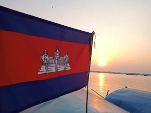 Krong KrachehTonle Mekong Homestay的船后方的旗帜与日落