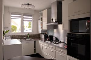 阿格诺Maison - Le Terra Verde - Terrasse的厨房配有白色橱柜和黑微波炉