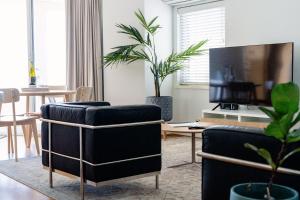 珀斯Cottesloe Beach View Apartments #11的客厅配有2把椅子和平面电视