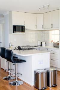 珀斯Cottesloe Beach View Apartments #11的厨房配有白色橱柜和带凳子的台面