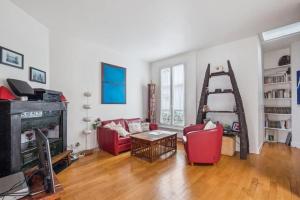 巴黎Charming Parisian Apartment的客厅配有2把红色椅子和壁炉
