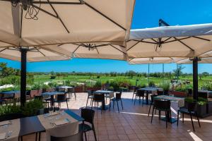 伊索拉阿尔巴勒拉Isola di Albarella Golf Hotel的一间带桌椅和遮阳伞的餐厅