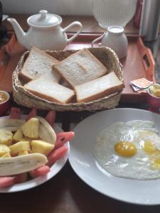 尼甘布Star Canal Cottage的一张桌子,上面放着烤面包片,鸡蛋和面包